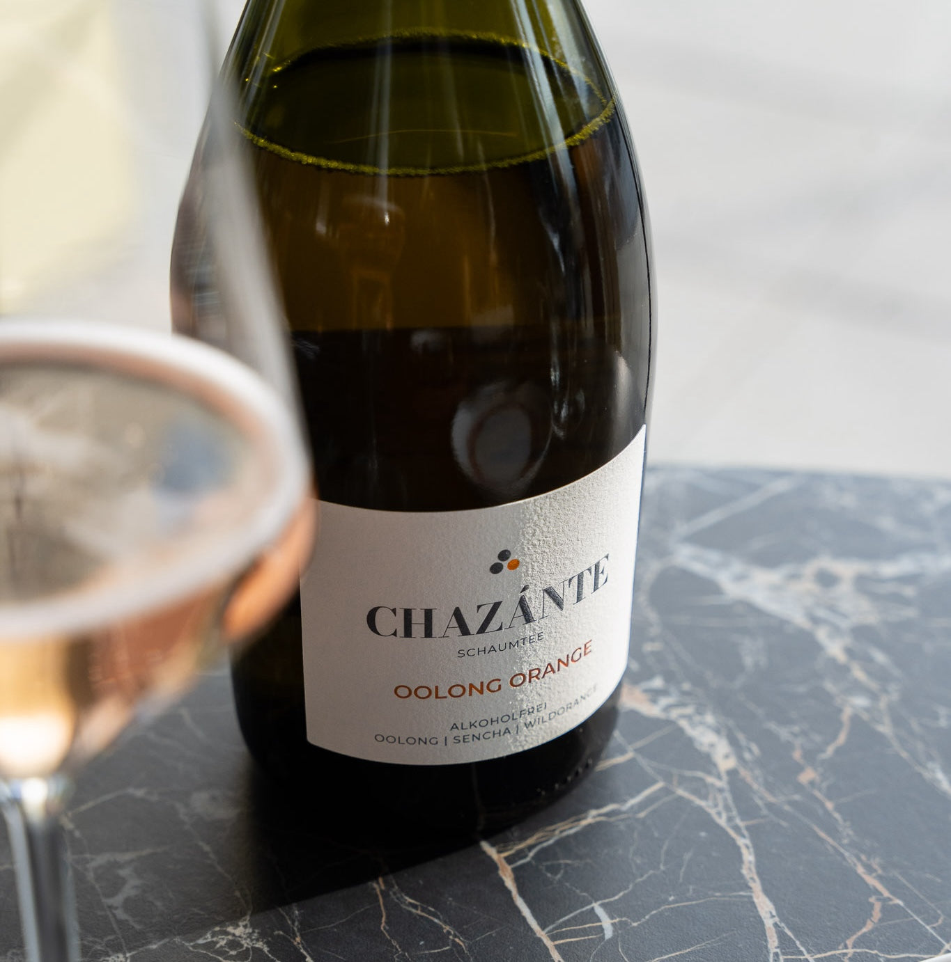 Chazánte alkoholfreier Sparkling Tea – Glas und Flasche stimmungsvoll im Sonnenlicht
